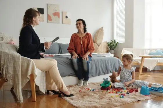 A social worker talking with a mother while her child plays nearby