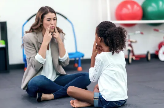 A speech pathologist practising sounds with a young girl